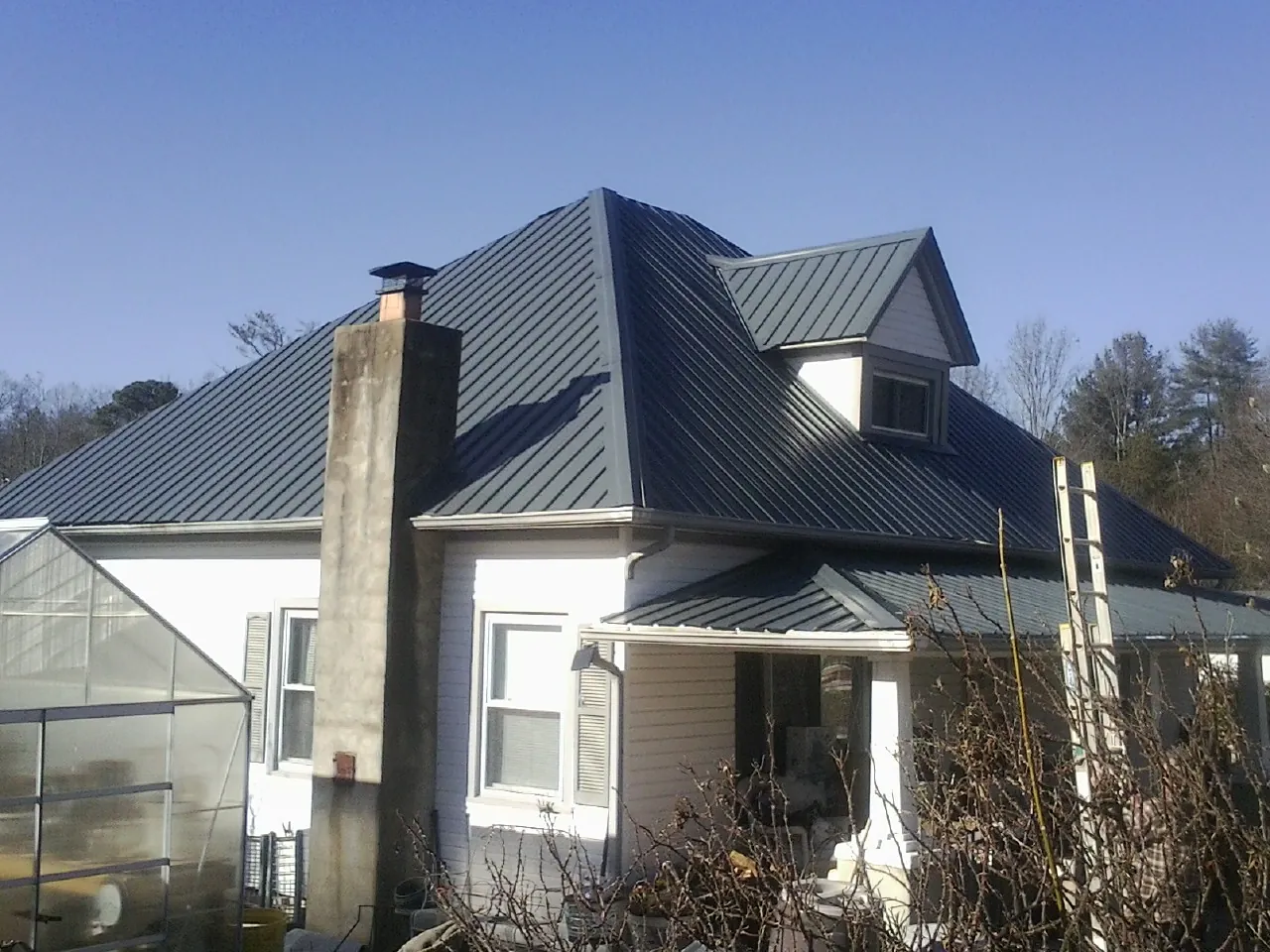 Dark blue standing seam metal roof on a white farmhouse with dormer — Slate & Tile Roof Repair by Roofing Brothers in Bangor