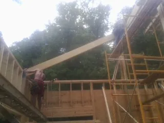 Carpenter raising a rafter beam on a new second story frame in Bangor