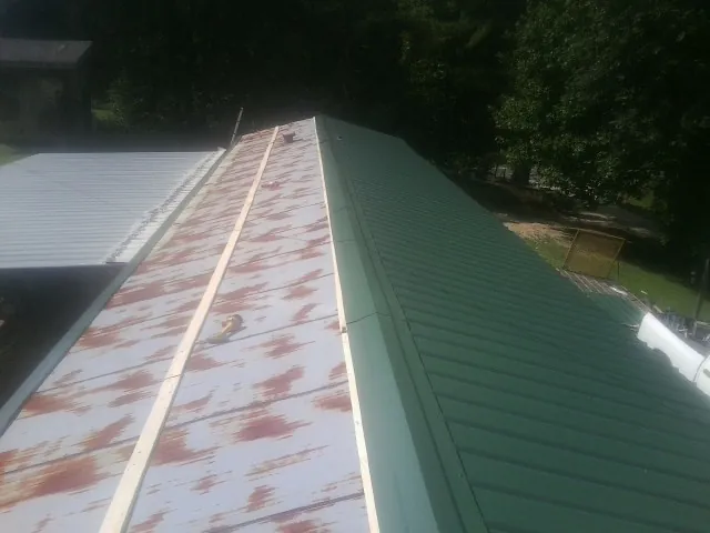 Old rusted panels beside newly installed green metal roofing — Wind Damage Roof Repair by Roofing Brothers in Bangor