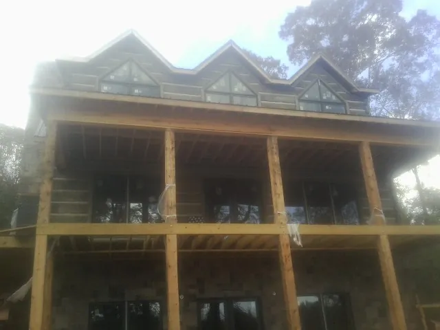 Dormers and porch framing on a large log home under construction — Roof Coating work by our crew in Bangor
