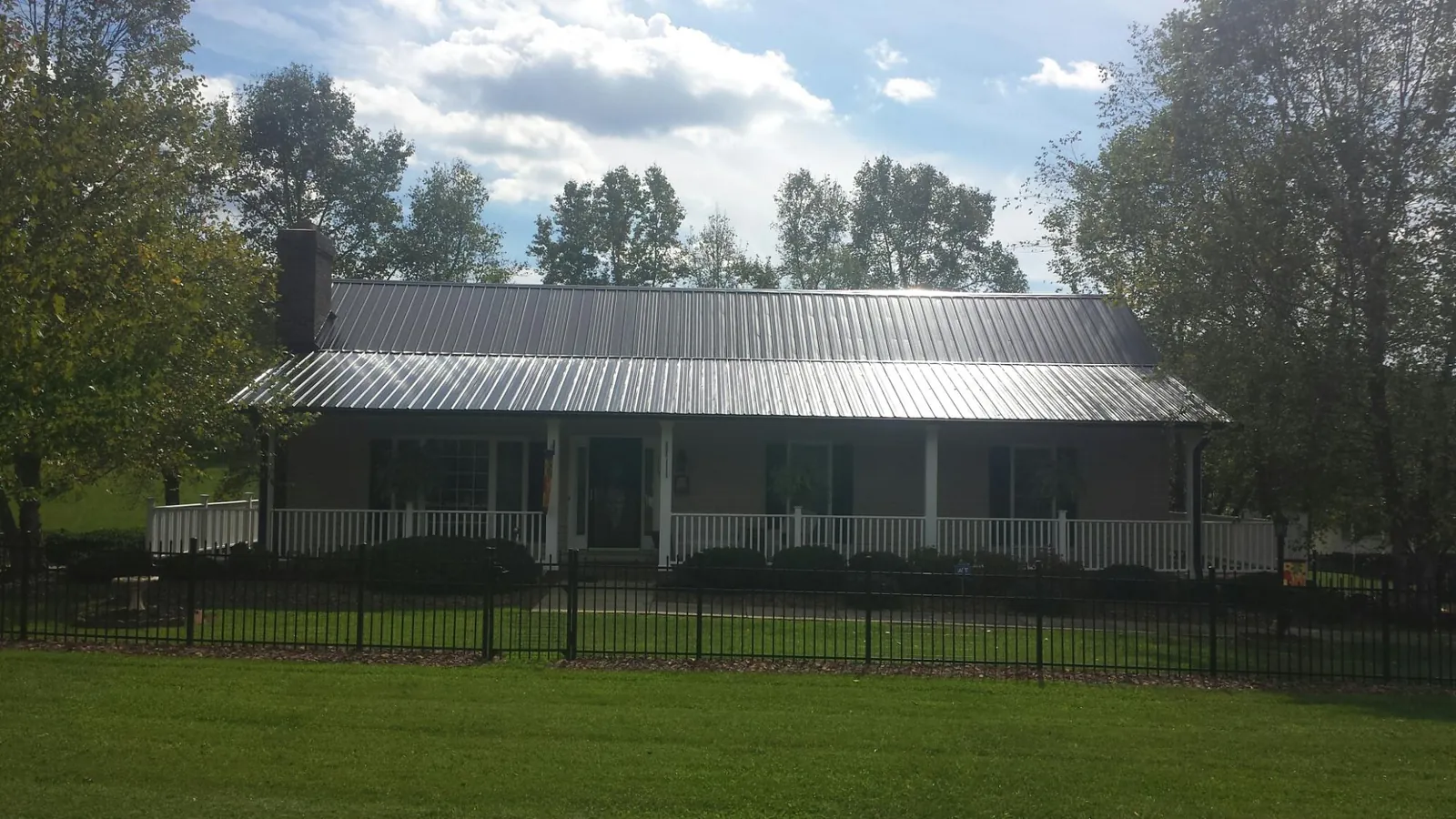 Gray metal roof on a brick ranch with a full width front porch — Gutter Guard Installation work by our crew in Bangor