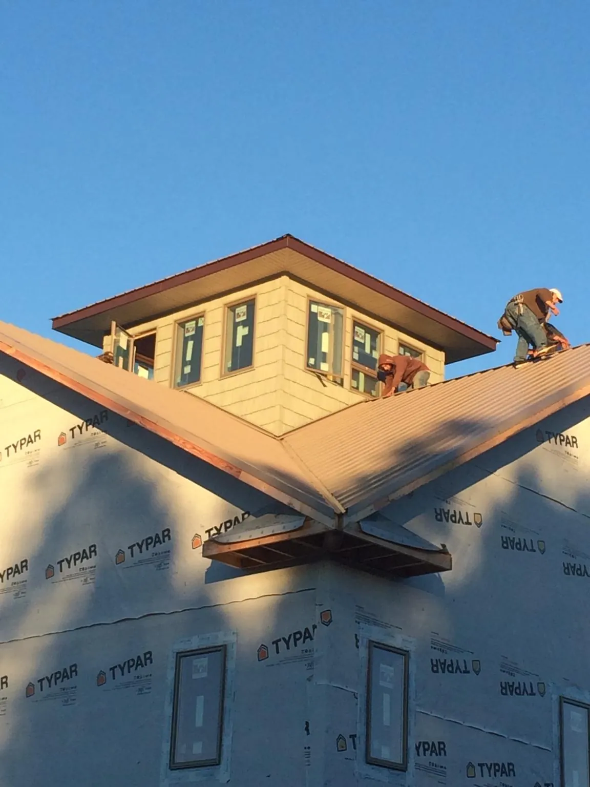 Roofers working around a rooftop cupola on a new metal roof at sunset — Roof Waterproofing in Bangor by Roofing Brothers